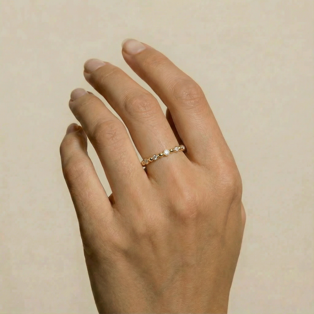 Hand with a delicate gold beaded ring on the ring finger
