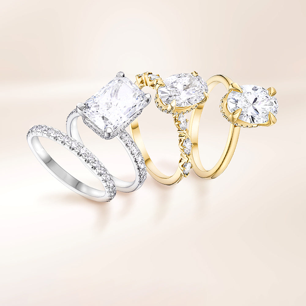 Three diamond engagement rings in silver and gold on a soft cream background